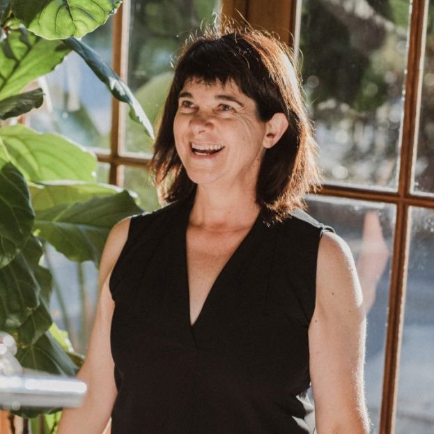 Photo of Helen Treloar, ACT trainer, dressed in black, smiling, in front of window